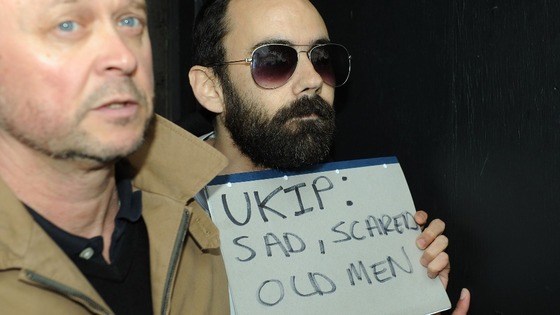 A man (right) is restrained after throwing an egg at Nigel Farage.