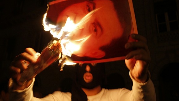 A protester burns a picture of Egypt's President Hosni Mubarak during clashes in Cairo January 28, 2011