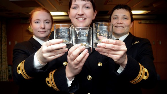 Three women in uniform smiling to camera, with glasses in their hands