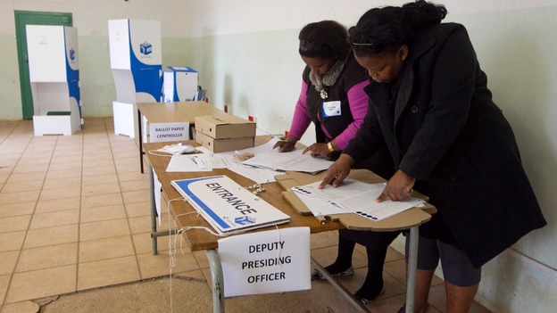 Election officials work in a classroom that has been transformed into a voting station in Embo.