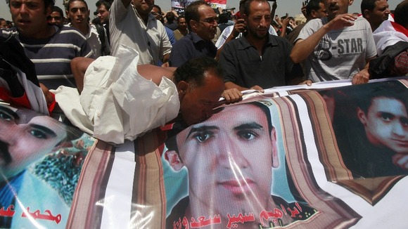 A man kisses a picture of a man who died during Egypt's revolutions after a court sentenced Mubarak to life in prison