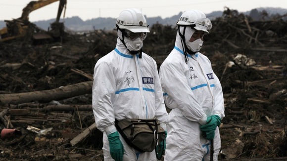Police officers in protective suits observe a moment of silence for those who were killed