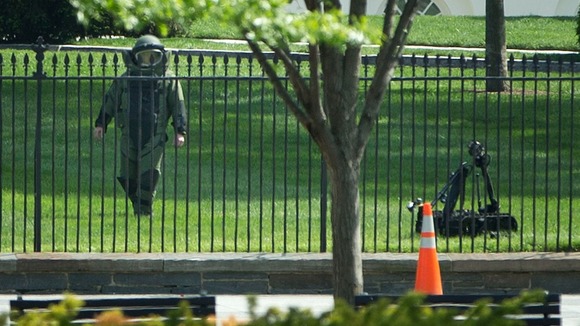 A bomb technician works with an explosives ordinance disposal robot to help recover an item thrown over the White House fence.