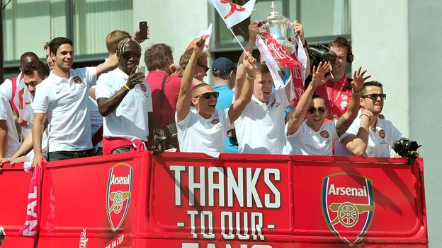 Goalkeeper Wojciech Szczesny holds the trophy aloft to cheering fans.