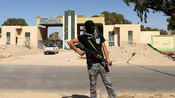 A militia stands guard in front of the entrance to a militia camp in Benghazi on 16 May