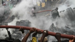 People help rescue workers extinguish a fire after a plane crashed into a neighbourhood in Ishaga district