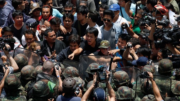 Protesters against military rule and soldiers deployed to control them confront each other at Bangkok's shopping district.