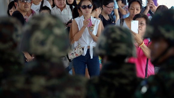 Commuters take pictures of soldiers blocking the access to a pedestrian bridge.