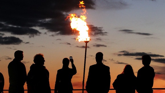 People view the Diamond Jubilee beacon at Edinburgh Castle beside Mons Meg Cannon as the sunsets