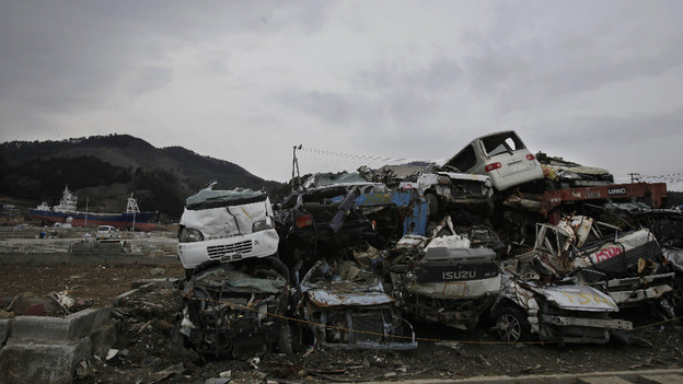 Cars destroyed by the March 11 tsunami are left abandoned as the 330 ton fishing vessel which was flung 800 metres