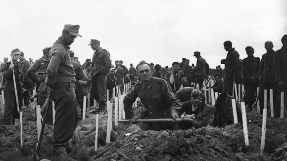 German soldiers captured by American forces bury some of the men killed during the assaults.