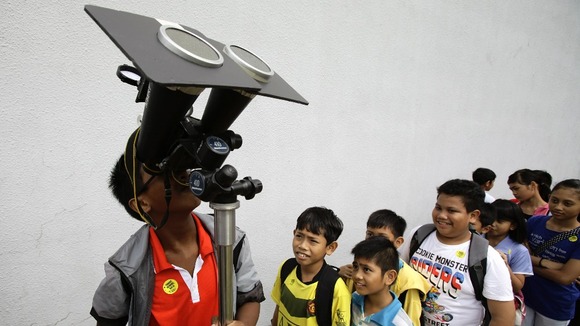 Children take turns to look at planet Venus transiting across the sun at a public viewing at the Singapore Science Centre.
