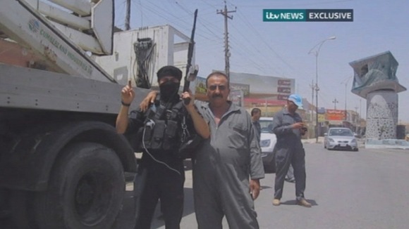 An ISIS fighter poses for the camera with an electricity worker.