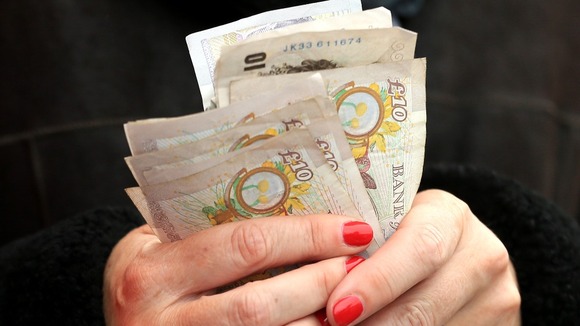 Woman holds money £10 notes in hands.