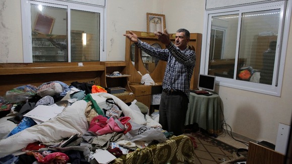 A man gestures after his home is searched and belongs strewn by Israeli soldiers.