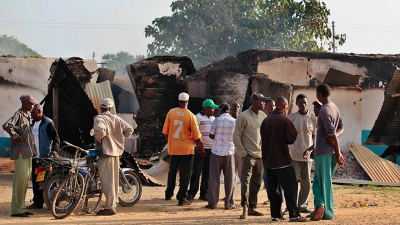 Residents stand in front of torched buildings in Mpeketoni, Kenya.