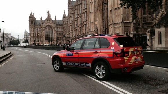 A police car is shown within the cordoned-off area in Westminster.