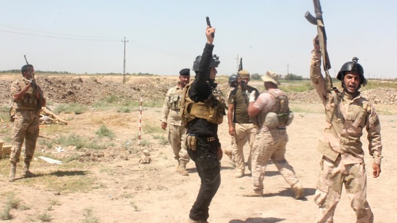 Members of the Iraqi security forces shout slogans as they carry weapons during clashes with Sunni militant group Isis.