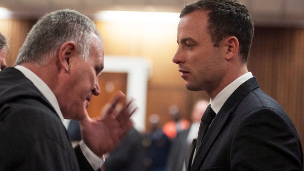Oscar Pistorius talks to his defence lawyer Barry Roux inside the Pretoria court where his trial is taking place.