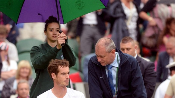 An umbrella is held over Andy Murray after his match against Kevin Anderson is suspended.