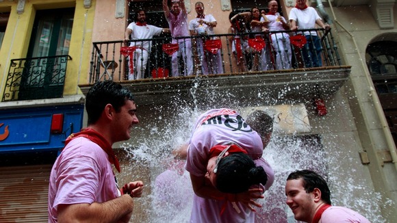 A woman is soaked with water from a balcony.