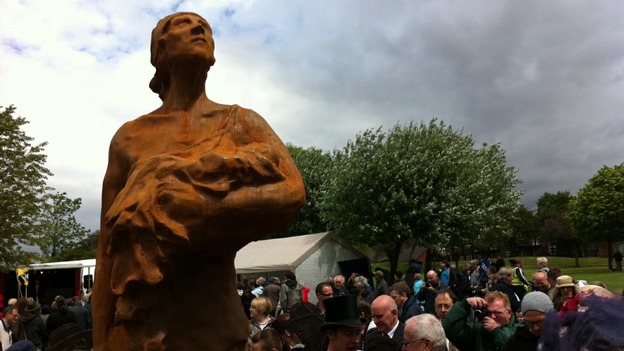 The figure cradles a baby in one hand