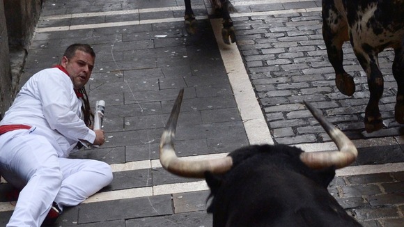 A man watches from the floor as a bull charges towards him.