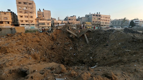 Palestinians stand atop the rubble of a house which police said was destroyed in an Israeli air strike.