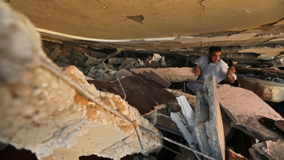 A Palestinian man searches for belongings under the rubble of a house in Gaza City.