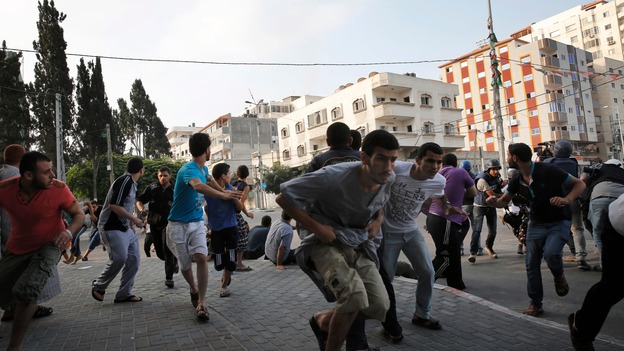 Palestinians take cover as warning Israeli air strikes are fired at a nearby building in Gaza City.