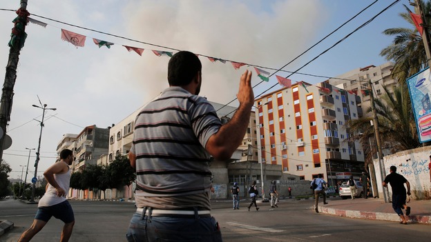 Palestinians react after warning Israeli air strikes hit a building in Gaza City.
