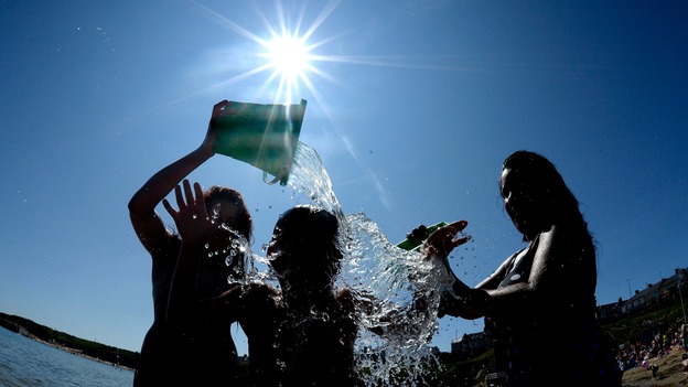 People throw water on each other at Cullercoats, North Tyneside as temperatures hit the high 20s.