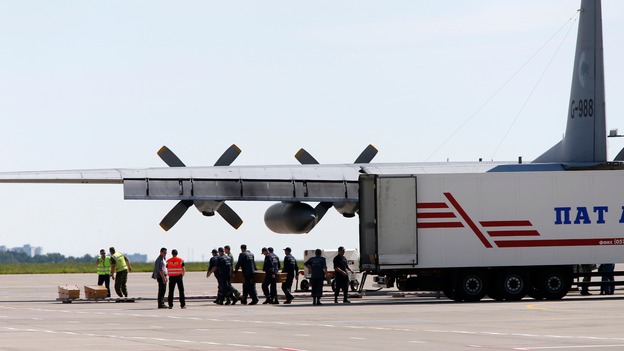 Officials carry coffins from a refrigerated lorry at Kharkiv airport.