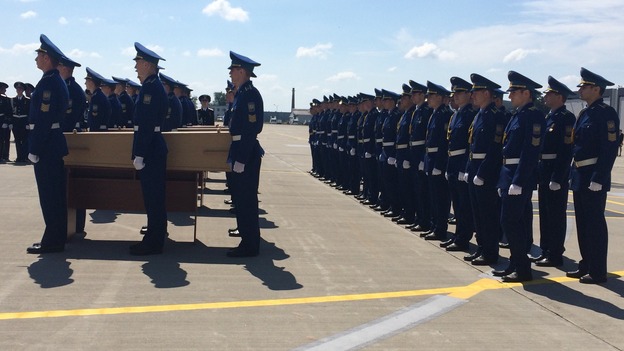 A ceremony is held for the victims before coffins are boarded on the plane.