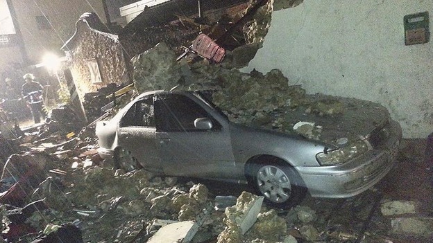 A car is seen covered in rubble from the wreckage