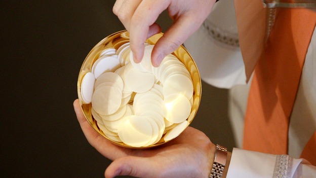 A Catholic priest holds communion.