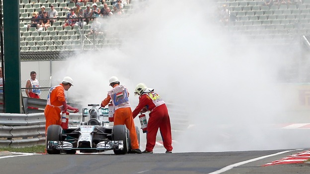 Firefighters try to extinguish fire on Lewis Hamilton's car.