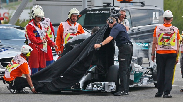Track marshals and Mercedes crew members cover Lewis Hamilton's car.