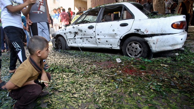 A boy looks at a damaged car after an explosion at a public garden in Gaza.