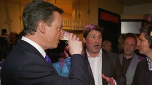 British Prime Minister David Cameron sinks a pint of Guinness.