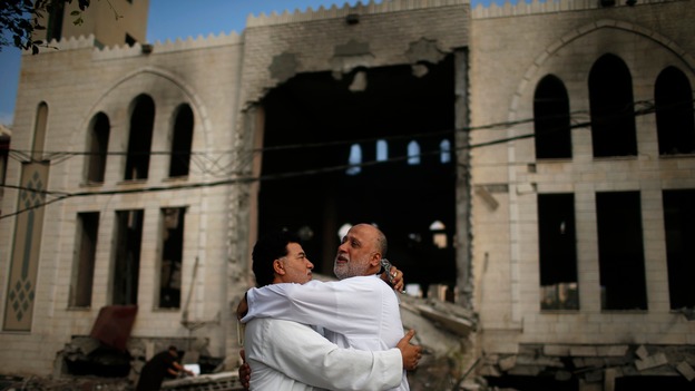 Palestinians stand in front of a mosque which witnesses said was hit in an Israeli air strike.
