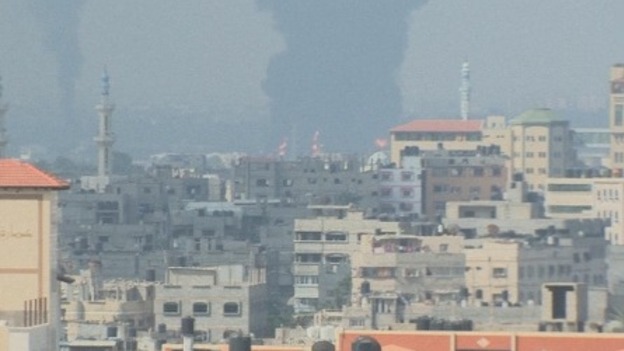The Gaza Strip's only power plant can be seen ablaze in the distance.
