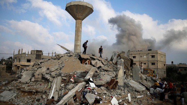 Palestinians search for victims as people gather atop the remains of a house in Rafah, southern Gaza.