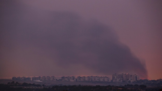 Israeli rocket is fired into the northern Gaza strip, as smoke rises from an airstrike at dusk.