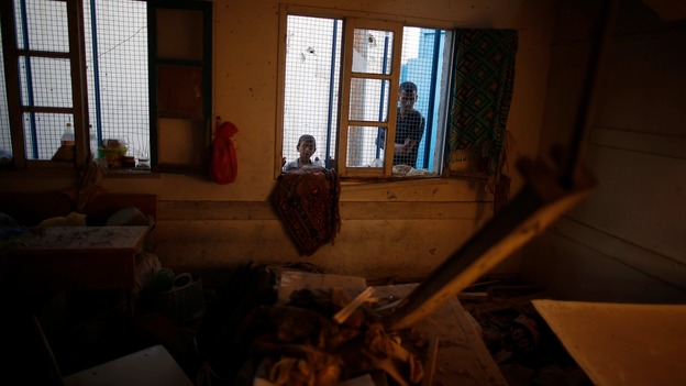Children look in at a destroyed classroom at the school.