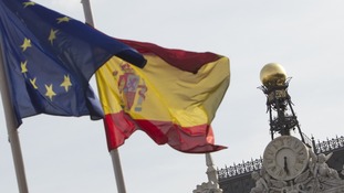 European and Spanish flags flutter next to the Bank of Spain in Madrid.