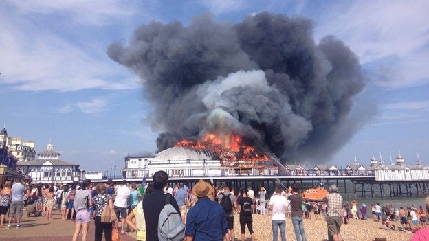 Holidaymakers and locals watch on as fire crews tackle the blaze on Eastbourne Pier.