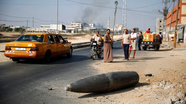 Palestinians look at an unexploded Israeli shell that landed near Deir Al-Balah in the central Gaza Strip.