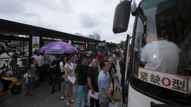 People line up in front of a bus to donate blood for the victims of the explosion.