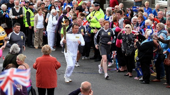 Callum Gordon carries the Olympic Flame on the Torch Relay leg between Scone Palace and Newburgh.